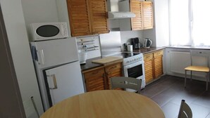 A compact kitchen with wooden cabinets, a microwave, a stove, and a sink.