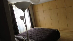 A room with a bed, a floor lamp, and a wardrobe.