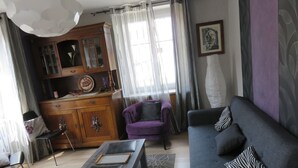 A living room with a sofa, a purple armchair, a wooden cabinet, and a coffee table.