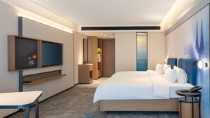 Una habitación de hotel con cama, televisión, escritorio y mesita de noche.