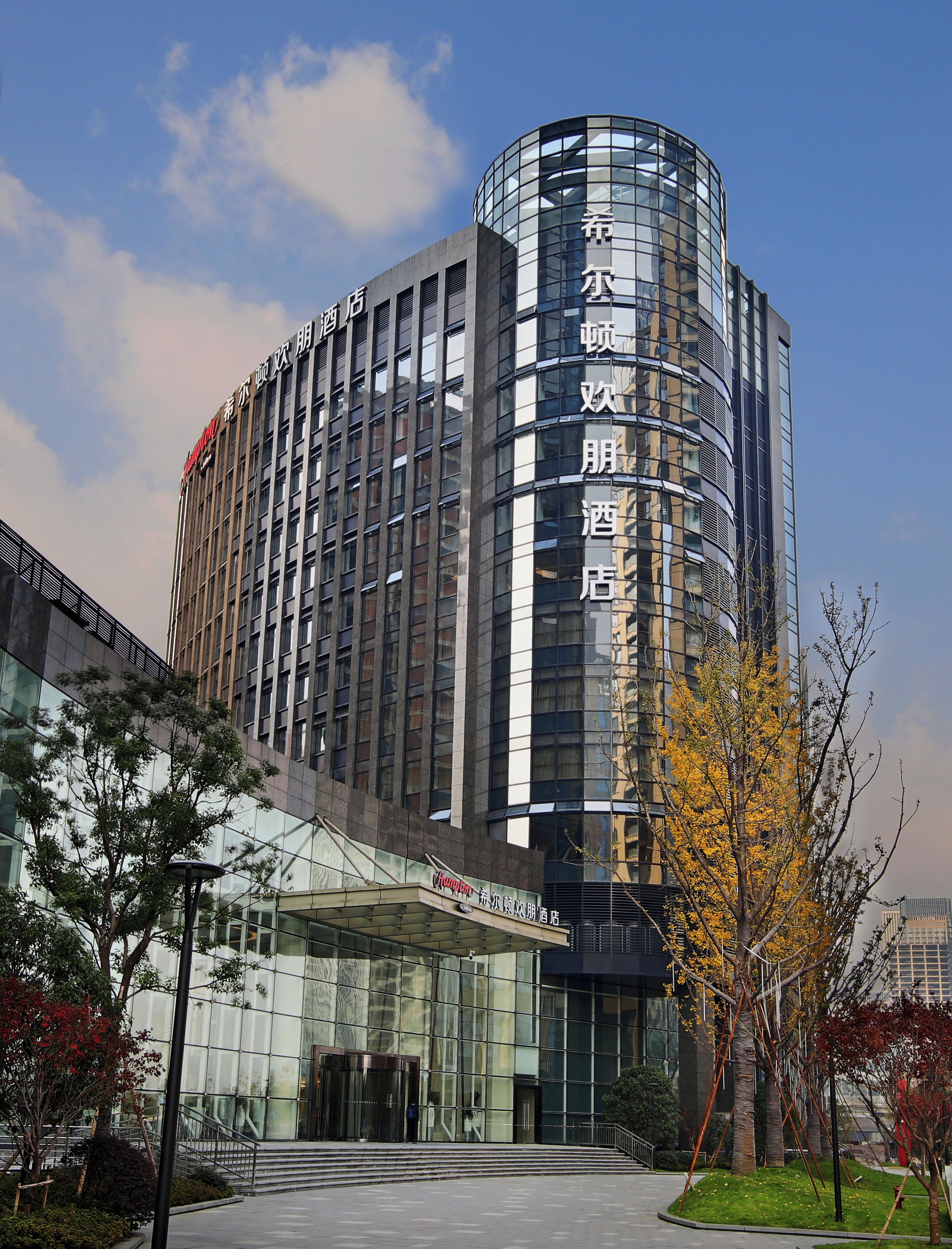 A modern hotel with a curved facade, large glass windows, and a prominent entrance with a canopy.