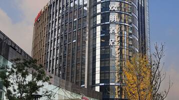 A modern hotel with a curved facade, large glass windows, and a prominent entrance with a canopy.