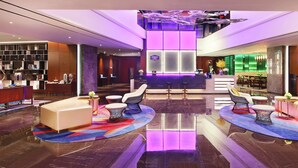 Un lobby moderno con mostrador de recepción, zona de estar y bar.