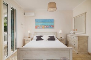A bedroom with a bed, bedside tables, a dresser, a large window, and a ceiling light.