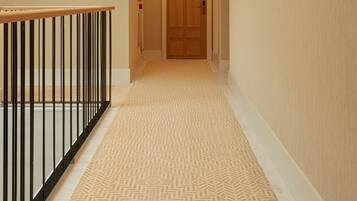 Un pasillo moderno de hotel con una puerta de madera, un ventilador de techo y una alfombra estampada.