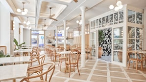 A spacious restaurant with high ceilings, wooden chairs, and a checkered floor. - ICON Malabar (Málaga)