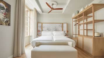 Un dormitorio con una cama grande, un armario de madera, un ventilador de techo y un cuadro en la pared.