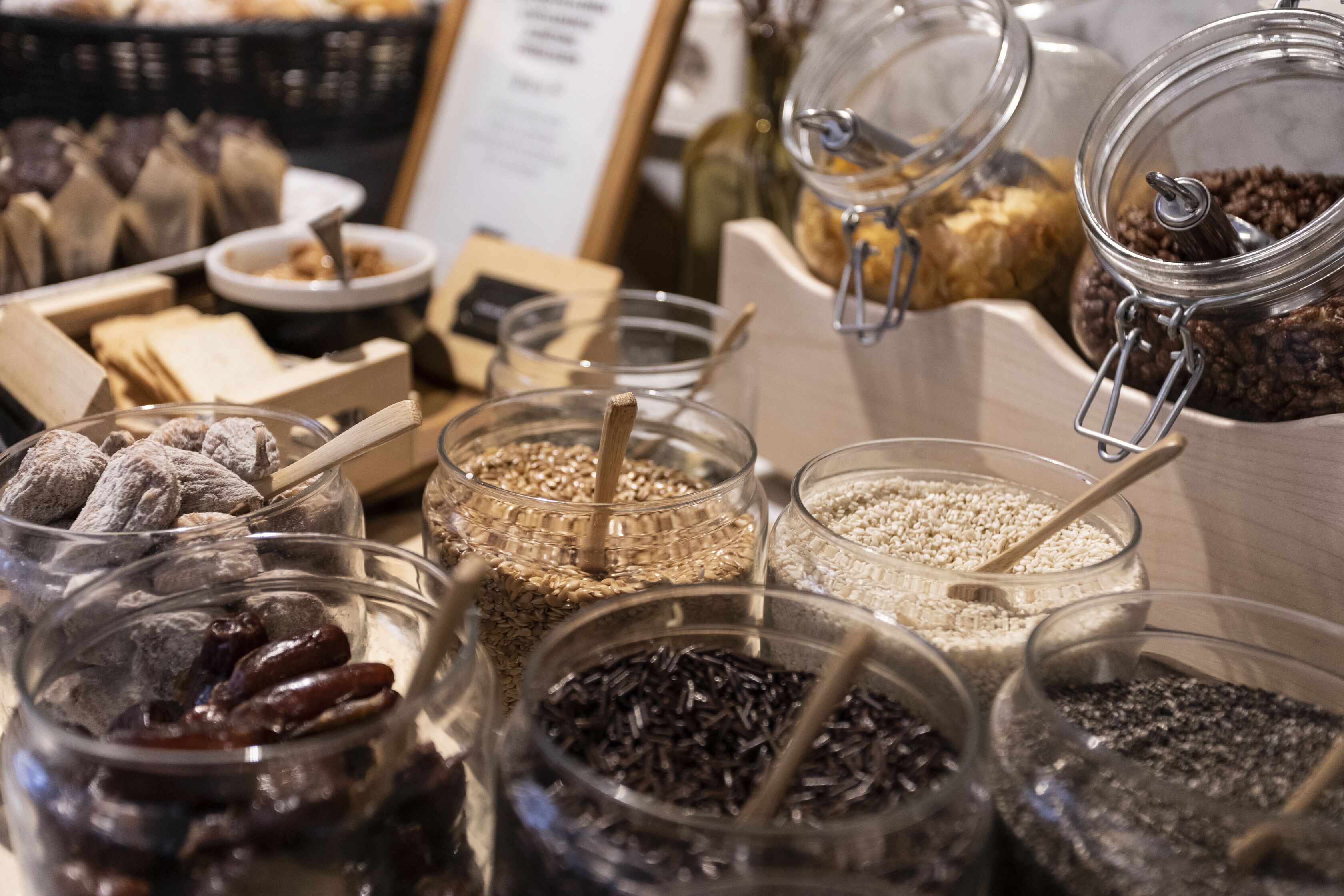 Diversos alimentos en frascos de vidrio, como nueces, semillas y frutas deshidratadas.