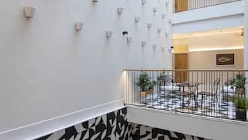 Un interior moderno con piso estampado, una pared blanca con luces empotradas y un balcón con mobiliario exterior.