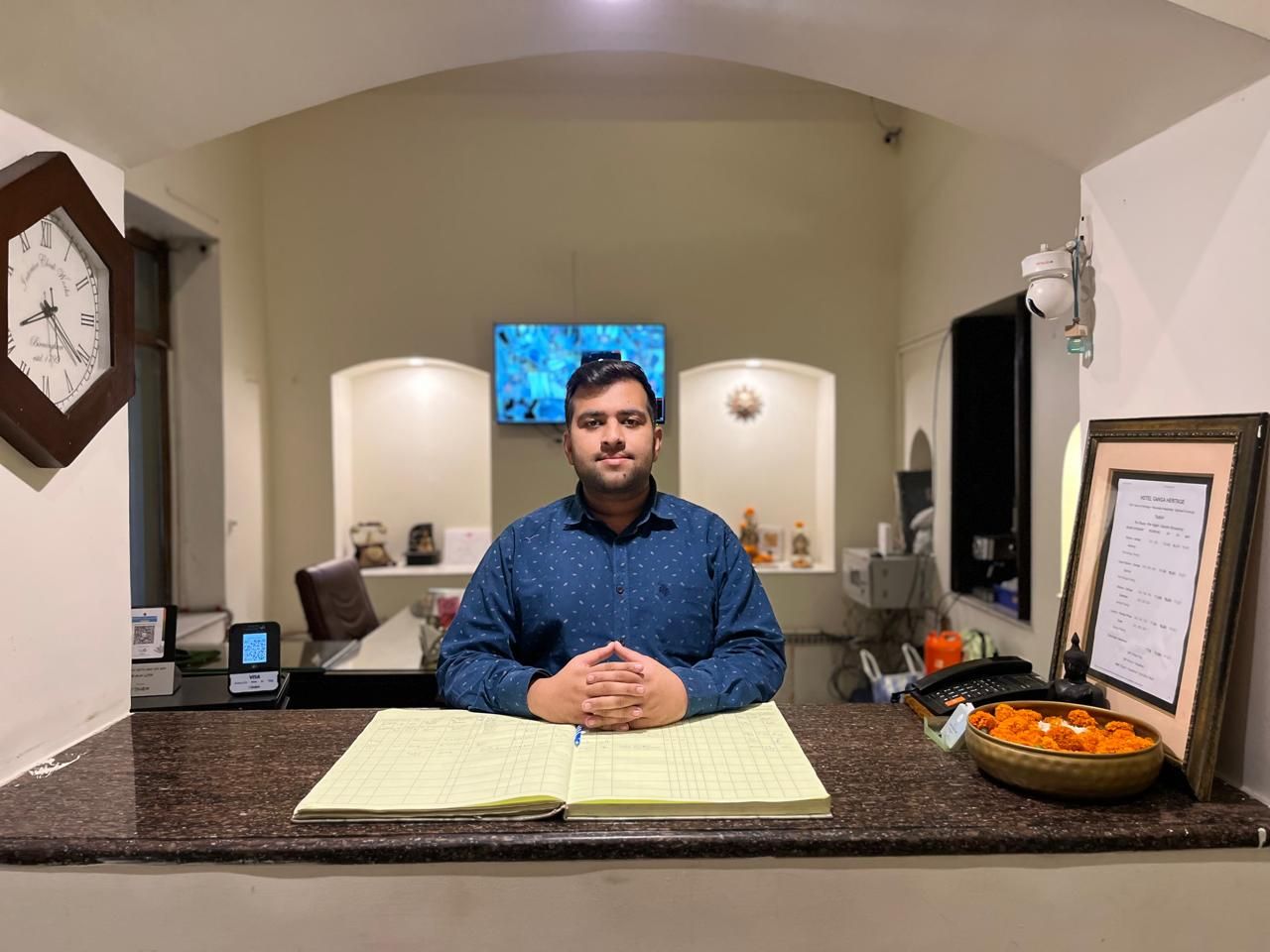 A person seated at a counter with a notebook, a framed menu, and a bowl of food.
