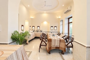 A dining area with a long table, chairs, and a ceiling fan.