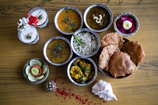 Une variété de plats indiens, notamment des currys, du riz et des pains plats, disposés sur une table en bois.