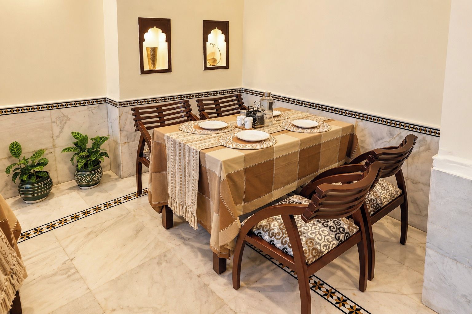 Un comedor con una mesa preparada para cuatro personas, rodeada de sillas con cojines estampados.