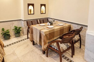 Un comedor con una mesa preparada para cuatro personas, rodeada de sillas con cojines estampados.
