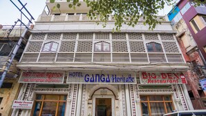 Um hotel com fachada tradicional, várias varandas e placas indicando agência de viagens e restaurante.