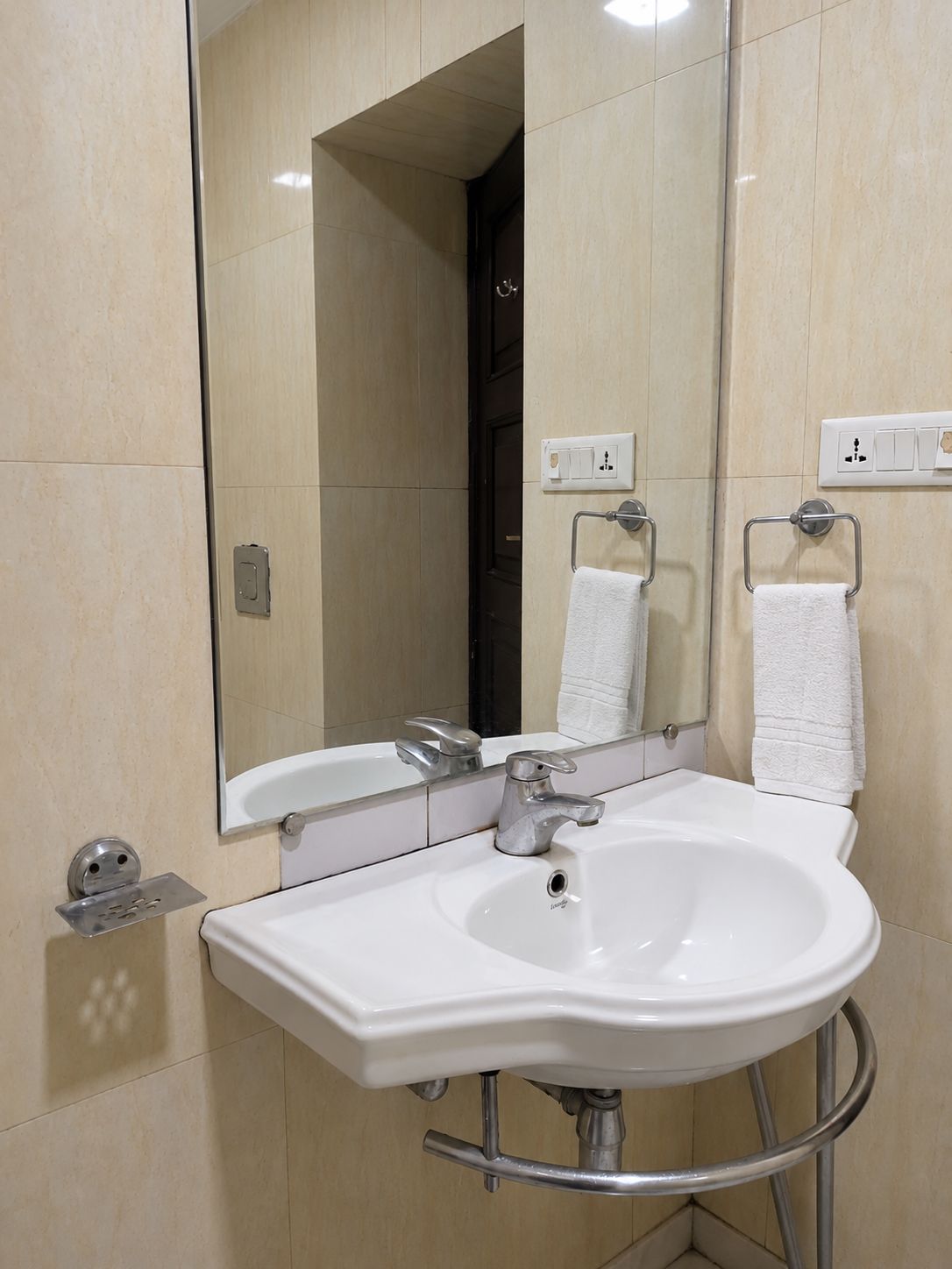 A bathroom with a white sink, a mirror, and two towel racks.