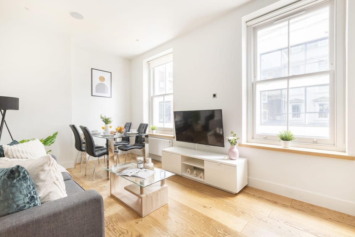 Una sala moderna con sofá, mesa de centro, televisión y zona de comedor.