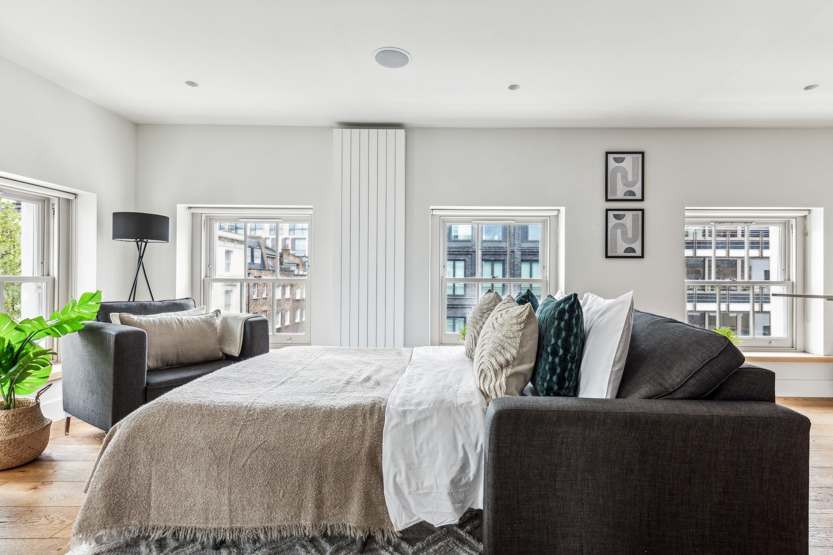 Een moderne slaapkamer met een groot bed, twee banken, een vloerlamp en een plant in pot.