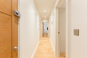 Un couloir avec des portes en bois, des murs blancs et un plancher en bois.