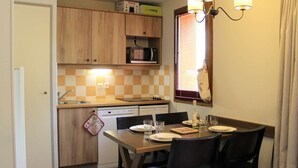 Une cuisine compacte dotée de meubles en bois, d’un four à micro-ondes, d’un lave-vaisselle et d’une table à manger avec des chaises.
