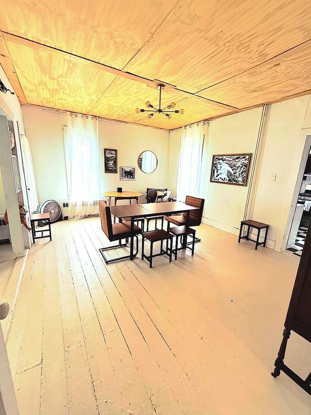 A dining area with a wooden ceiling, a round table, and chairs.