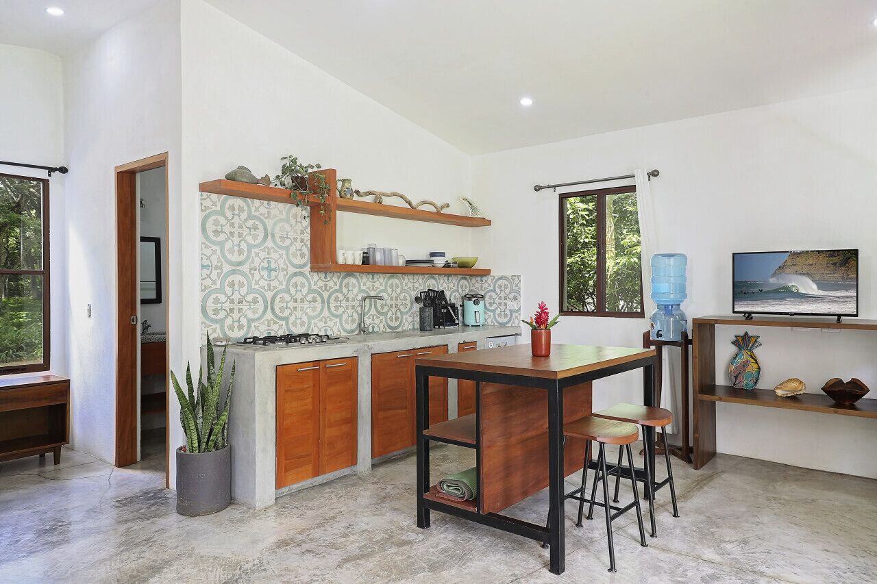 Ett modernt kök med en central köksö, träskåp och en kakelbeklädd vägg bakom arbetsbänken.