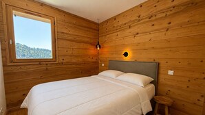 A bedroom with a wooden wall, a bed, a window, and a nightstand.