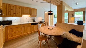 A kitchen with wooden cabinets, a round dining table, and a black furry rug.