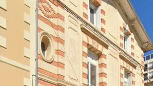 Un bâtiment à la façade beige, agrémenté de détails en briques rouges et doté d’une fenêtre circulaire.