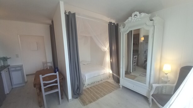 Une chambre à coucher avec un lit, une chaise, un bureau, un miroir et une lampe.