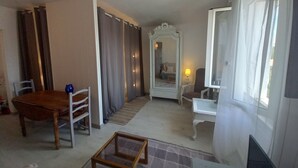 Une pièce comprenant une table à manger en bois, des chaises, un miroir, une petite table et une fenêtre avec des rideaux.