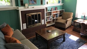 Ein Wohnzimmer mit Kamin, Bücherregal, Sofa und Sessel.