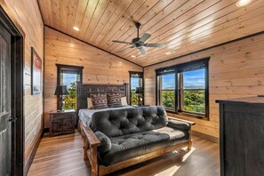 A bedroom with a large bed, a wooden ceiling, and a view of the outdoors.