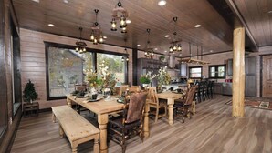 Una cocina amplia con piso de madera, una gran mesa de comedor para seis personas y lámparas colgantes.