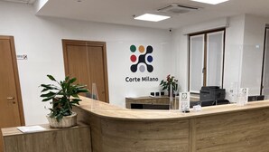 A reception desk with a logo, a plant, and a sign indicating 'Corte Milano'. - Corte Milano - Hostel (Rozzano)