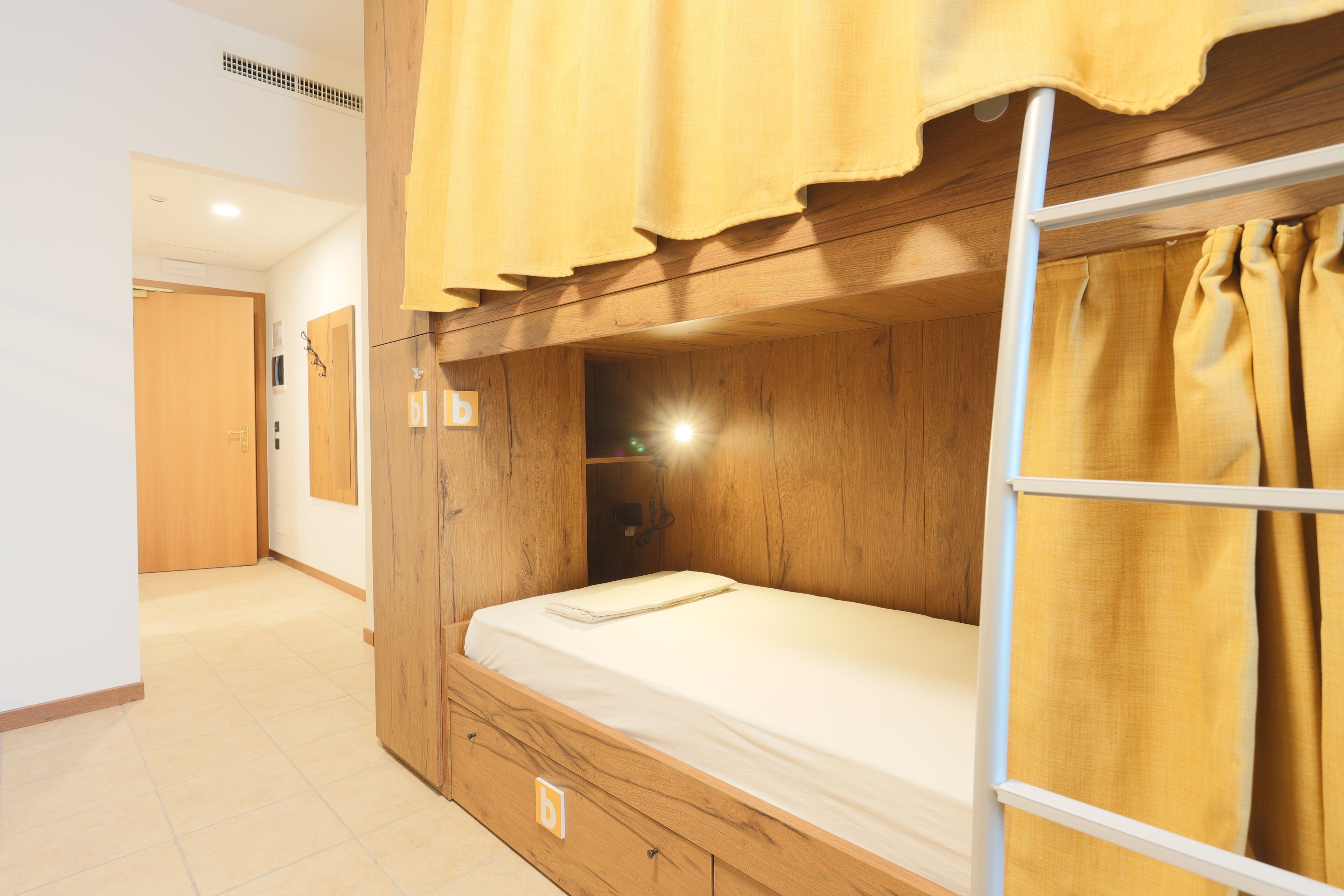 Une chambre avec un lit superposé, des murs en bois et un rideau jaune.