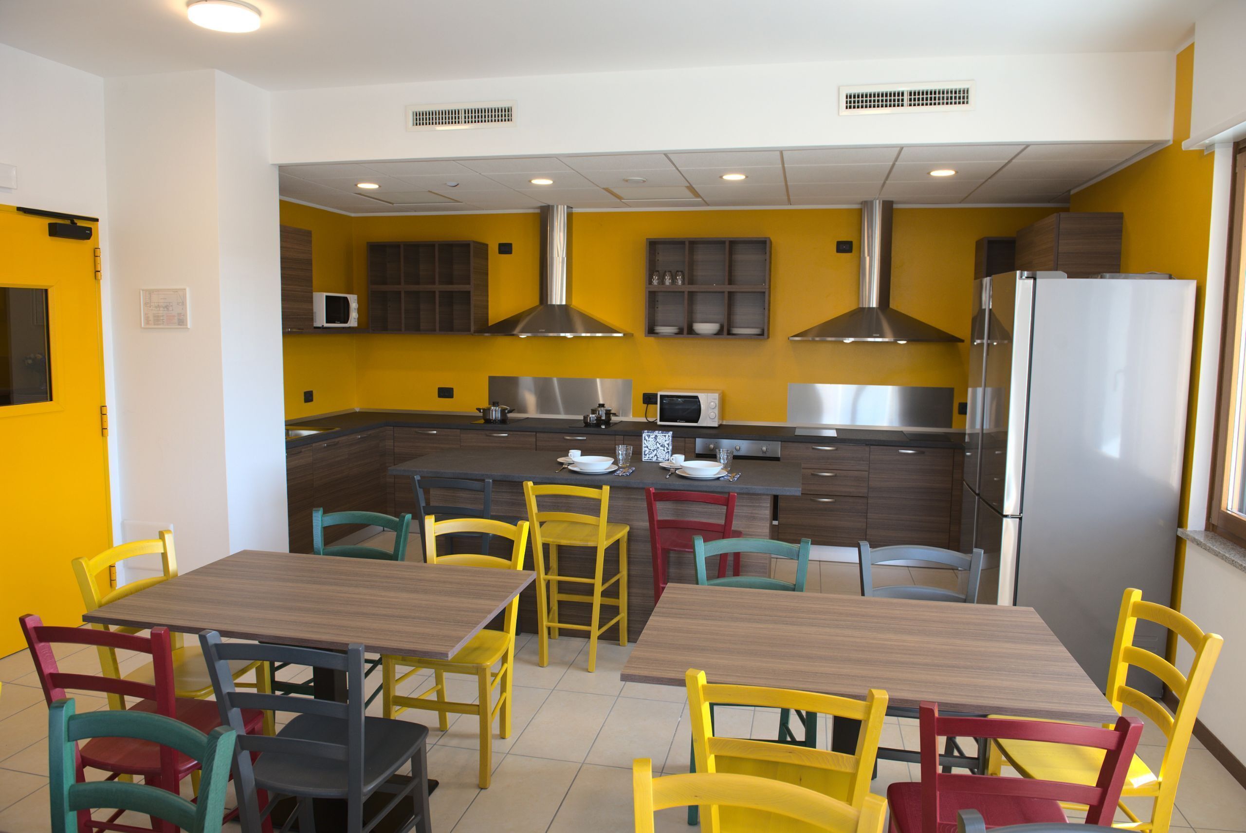 A modern kitchen with yellow walls, stainless steel appliances, and a central island with seating.