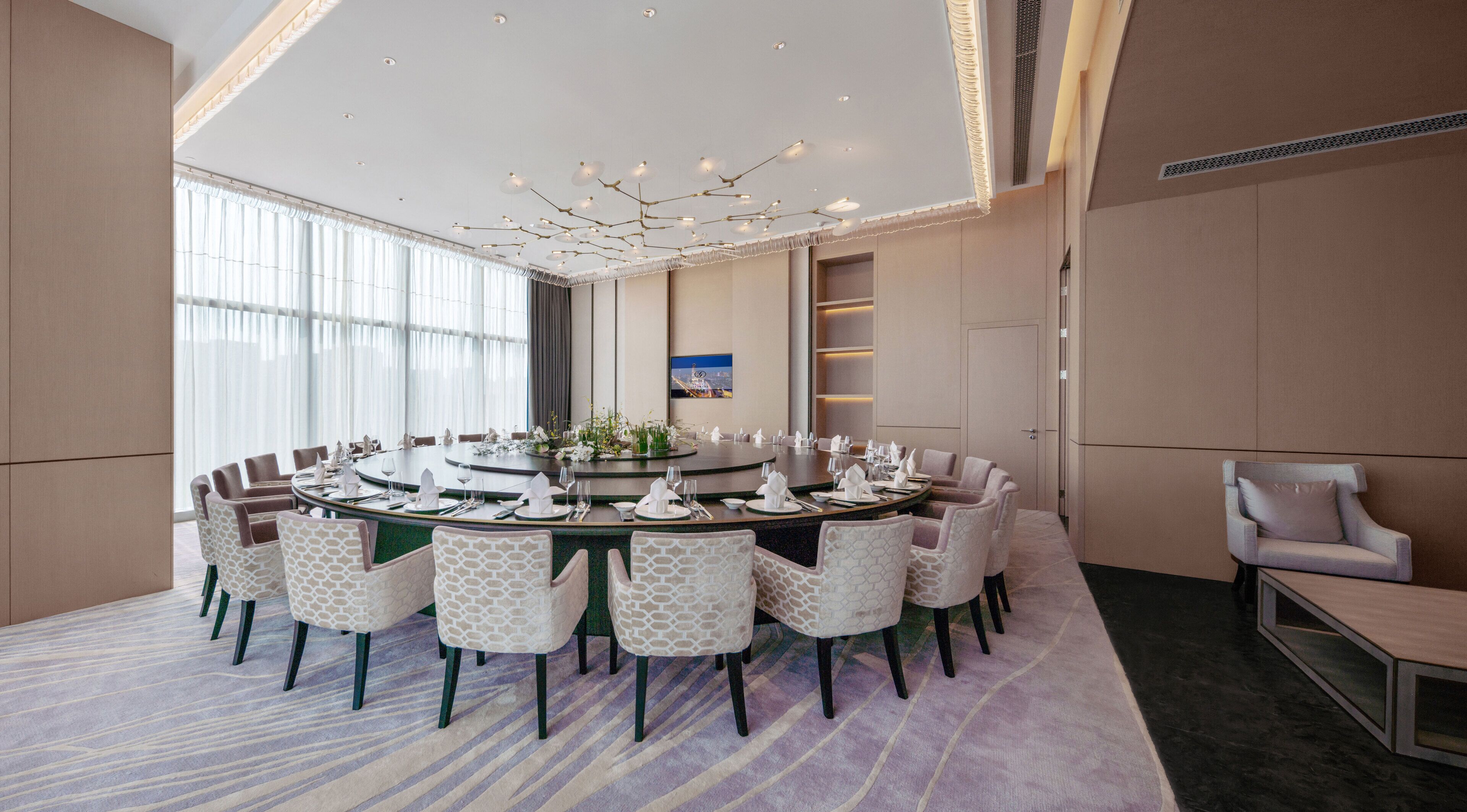 A conference room with a round table, chairs, and a chandelier.