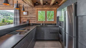Eine moderne Küche mit dunklen Schränken, Edelstahlgeräten und einer Holzbeschichtung an der Decke.