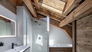 Ein modernes Badezimmer mit Glasdusche, weißem Waschbecken und Holzboden.