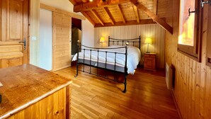 Un dormitorio de madera con cama, mesitas de noche y techo de madera.