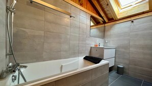Un baño moderno con bañera, ducha y tragaluz.