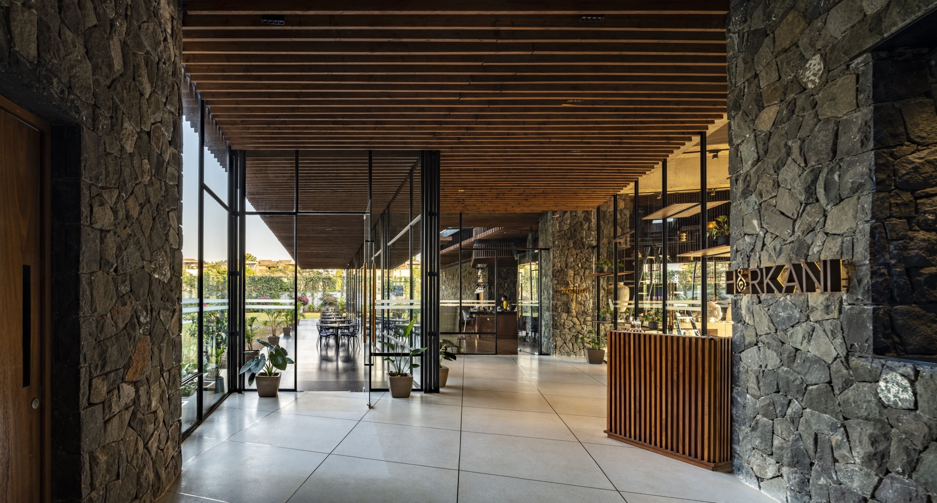 A spacious interior with a stone wall, wooden ceiling, and large windows.