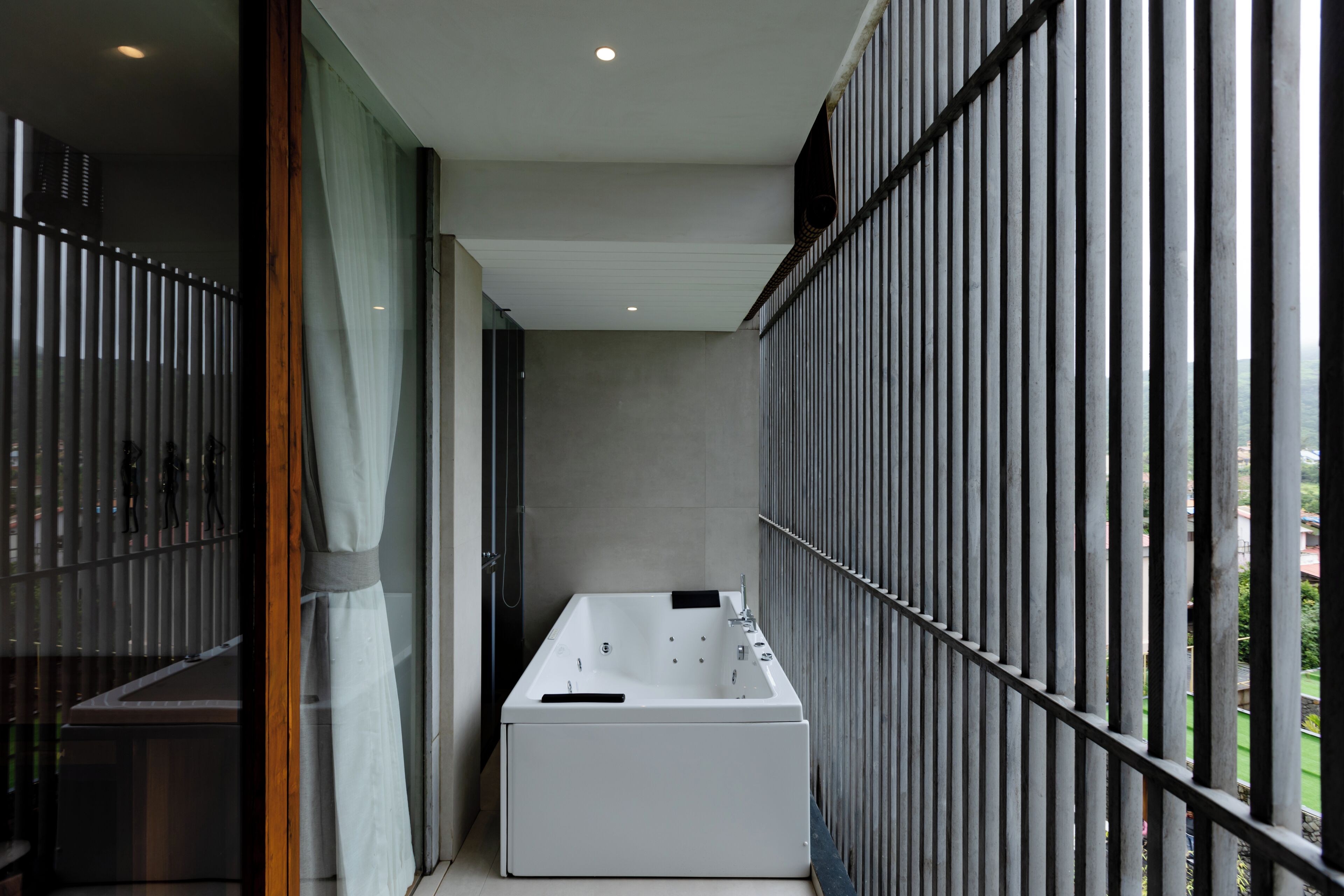 Un baño moderno con una bañera independiente, un box de ducha de vidrio y vistas a través de una barandilla de metal.