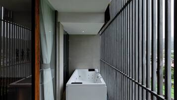 Un baño moderno con una bañera independiente, un box de ducha de vidrio y vistas a través de una barandilla de metal.