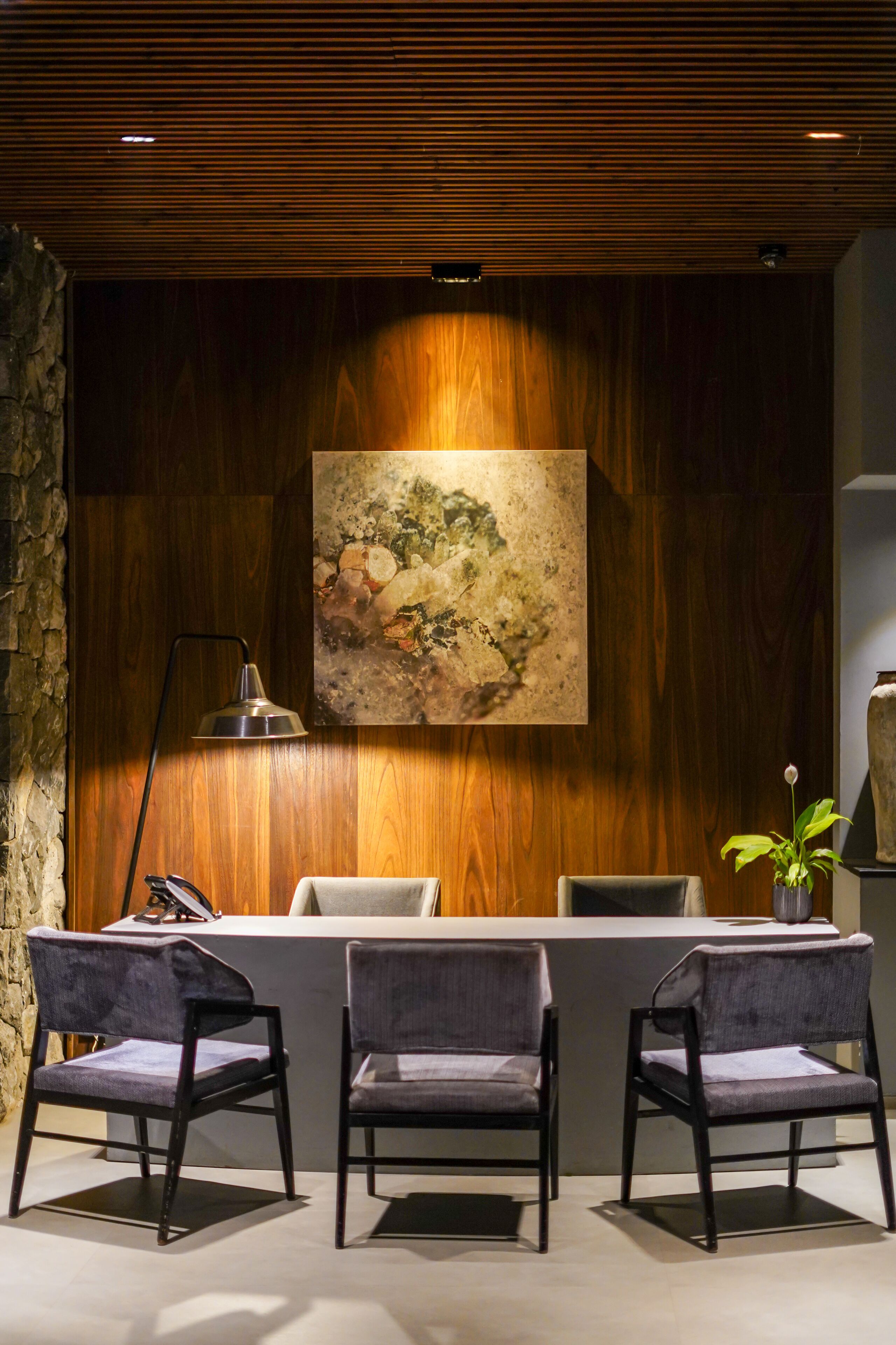 Un área de recepción con pared de madera, un cuadro y tres sillas.