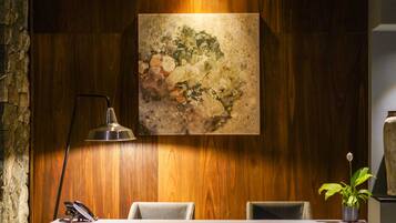 Un área de recepción con pared de madera, un cuadro y tres sillas.