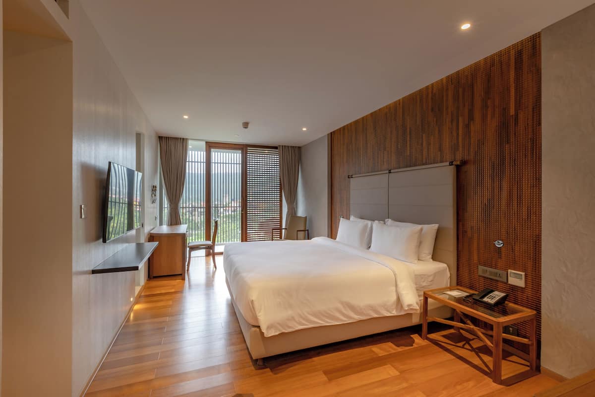 A modern hotel room with a large bed, a desk, and a TV.