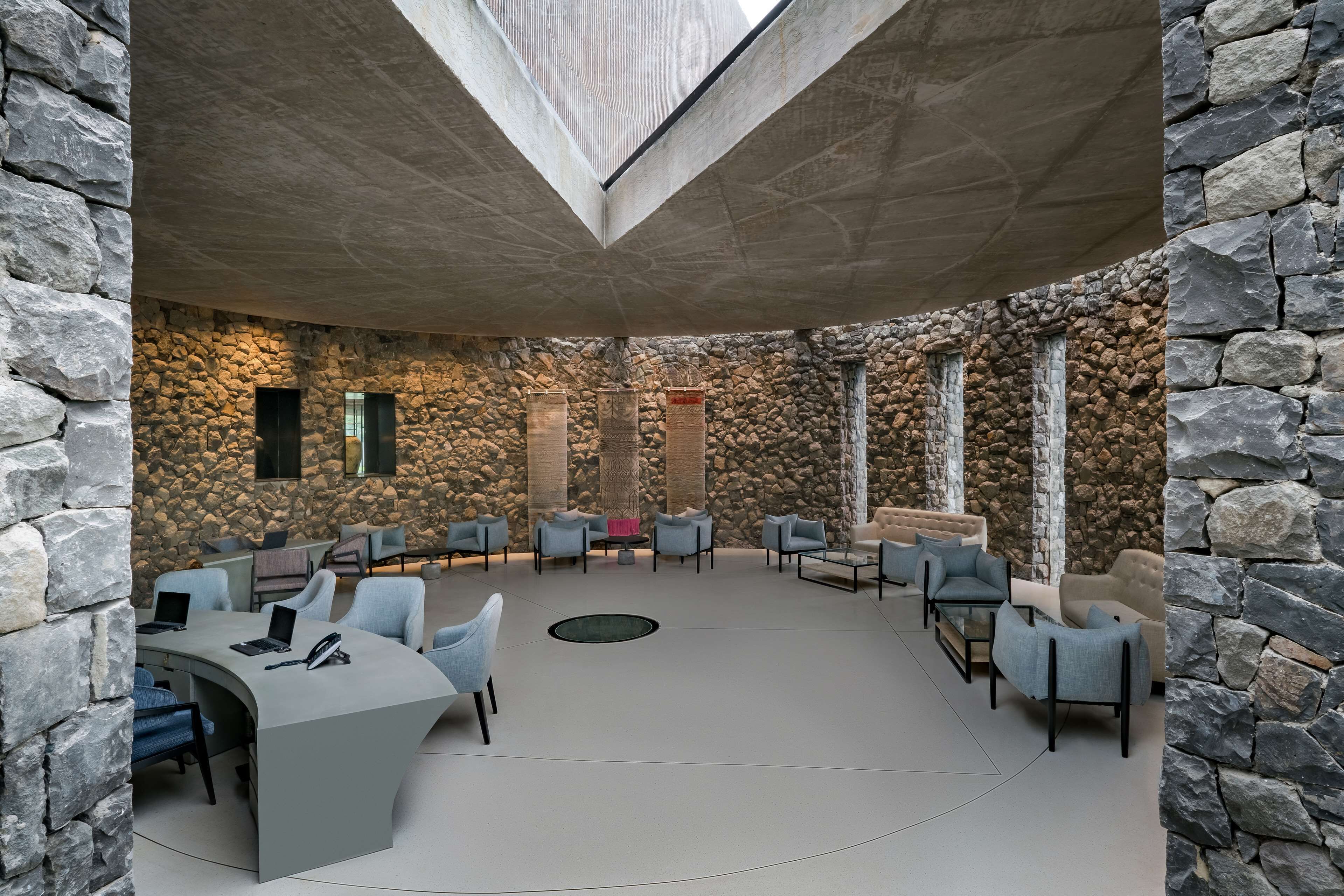 A modern interior with stone walls, a central seating area, and a skylight.