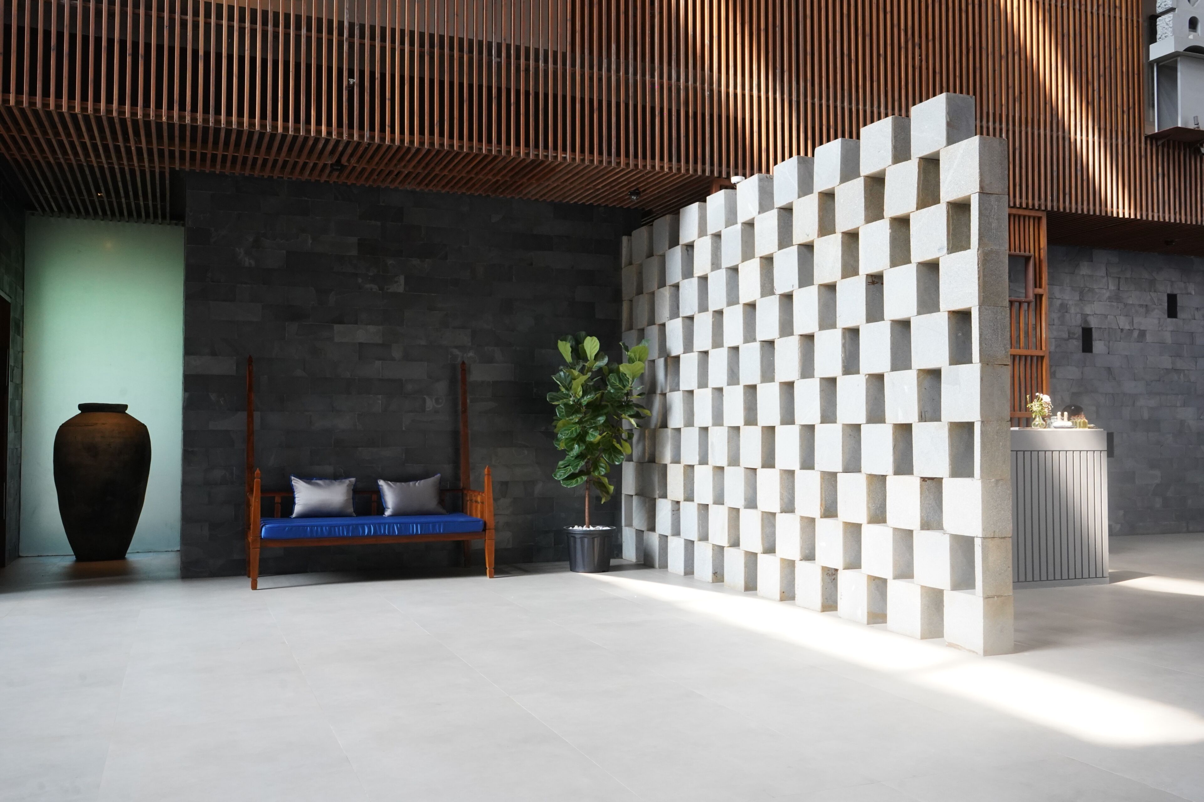 A modern interior with a stone wall, a wooden bench, a potted plant, and a geometric wall feature.